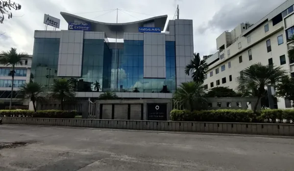 AMR Tech Park AMR Tech Park, Bangalore — glass-fronted office building with tenant signage across the upper floors and palms along the road frontage